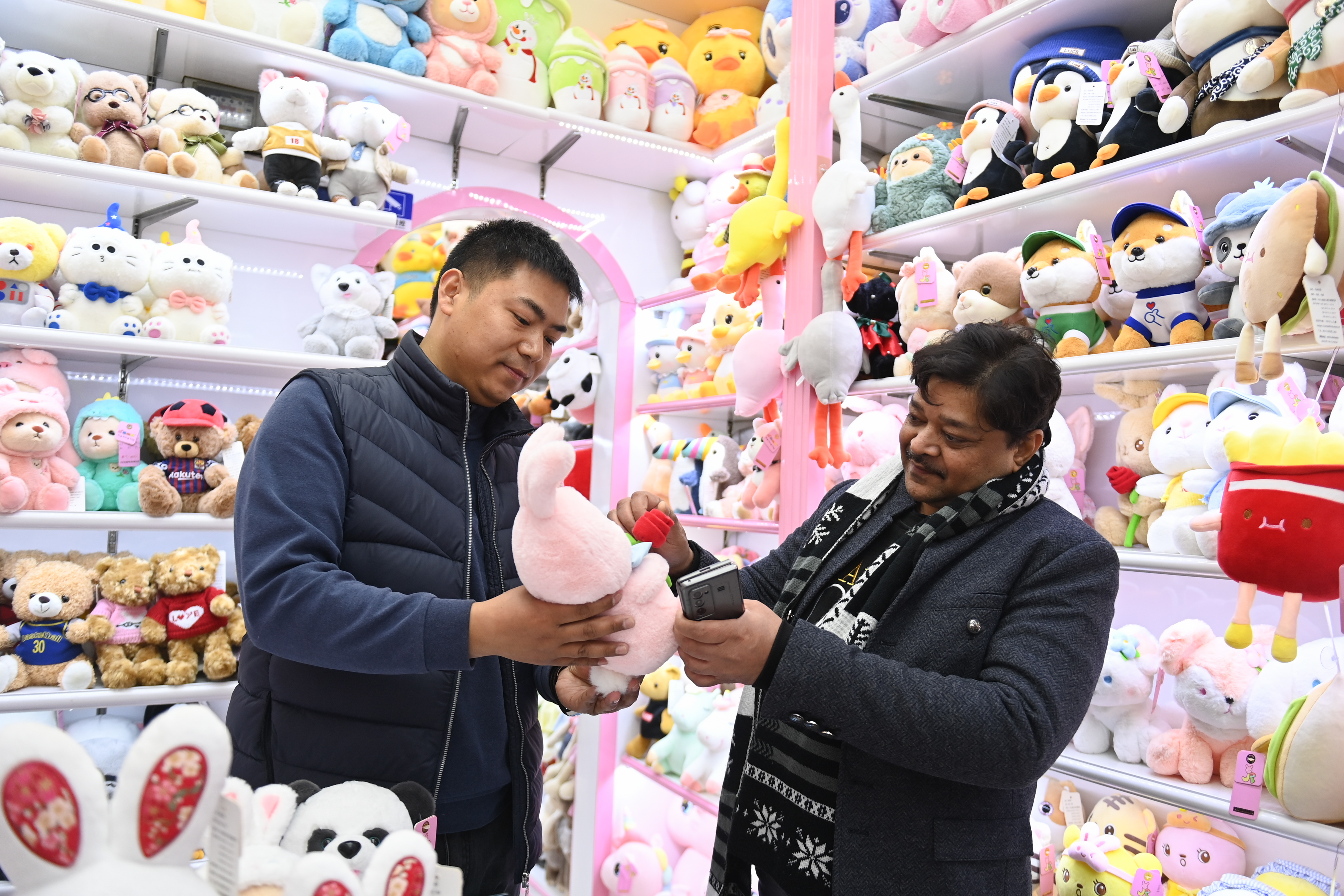 2023年2月2日，來自印度的客商（右）在義烏國際商貿(mào)城的一家玩具店鋪內(nèi)選購。
